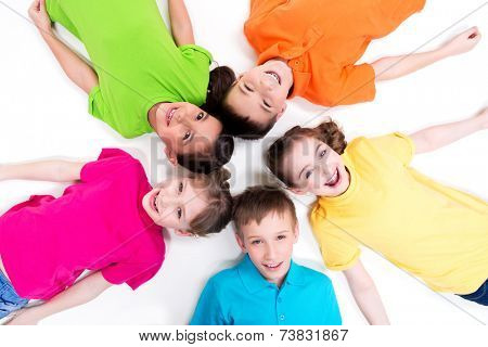 Five smiling children lying on the floor in a circle in bright t-shirts. Top view. Isolated on white.