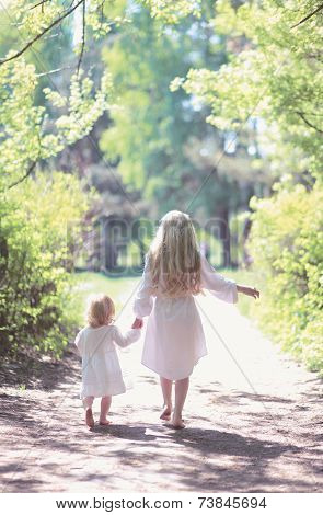 Two Sisters Holding Hands Walking In The Forest