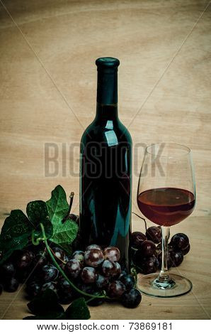 Wine Bottles With Glass And Red Grapes , Wooden Background
