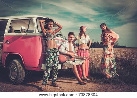 Multi-ethnic hippie friends with guitar on a road trip