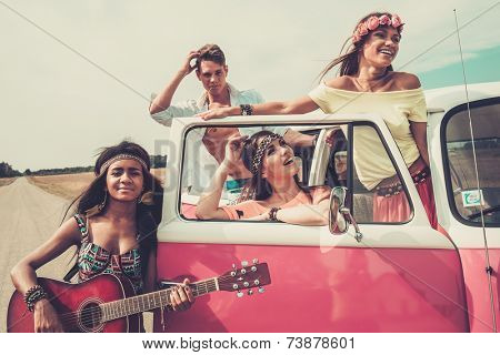 Multi-ethnic hippie friends with guitar on a road trip
