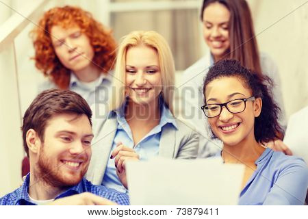 business, office and startup concept - smiling creative team with papers and take away coffee on staircase