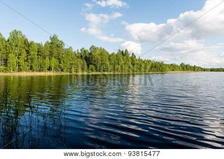 White Clouds On The Blue Sky Over Blue Lake
