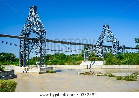 Gas pipe lines that laid through muddy river and green forest in summer scenery Romania.