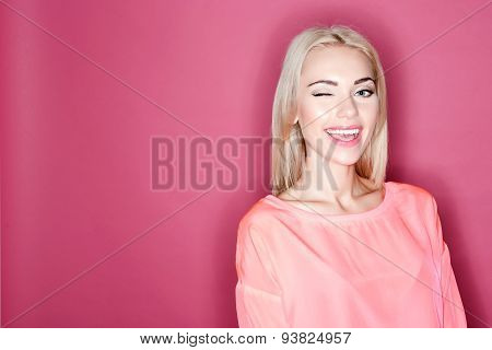 Pretty smiling girl winking on pink background