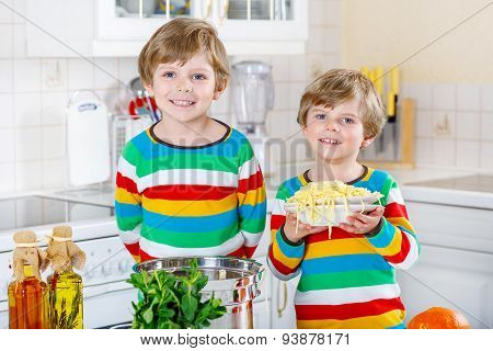 Two Little Kid Boys Eating Spaghetti In Domestic Kitchen.