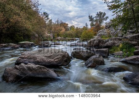 Mountain stream is surrounded with autumn trees.