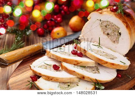 Stuffed turkey breast with pomegranate and rosemary on cutting board.