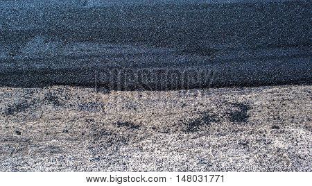 Background asphalt just applied on the roadway. This is the wearing course which is applied regularly because worn by vehicular traffic