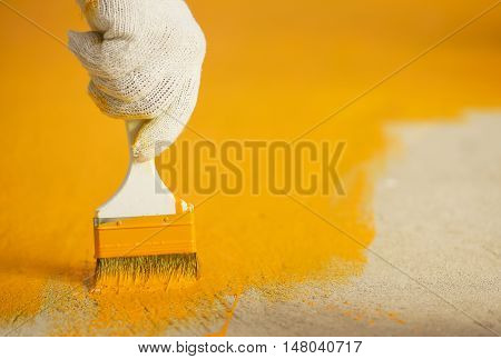 Hand with brush and yellow paint in construction site