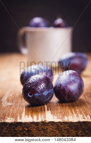 some blue raw ripe plums in old cup in studio