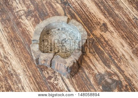 Wooden ashtray on a brown wooden table.