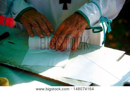 man wrapping wax candle into paper at market palce