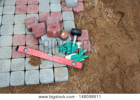 Pavement details stone blocks rubber hammer level gloves and tape measure