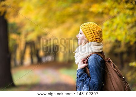 Beautiful woman with backback on a walk in colorful autumn forest
