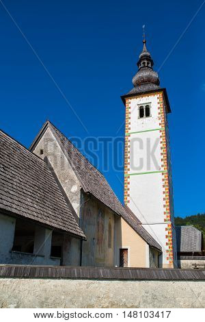 BOHINJ LAKE SLOVENIA - AUGUST 25 2016: Church of St. John the Baptist at Bohinj Lake is over 700 years old and is a beautiful example of Middle Age architecture and fresco painting in Slovenia.