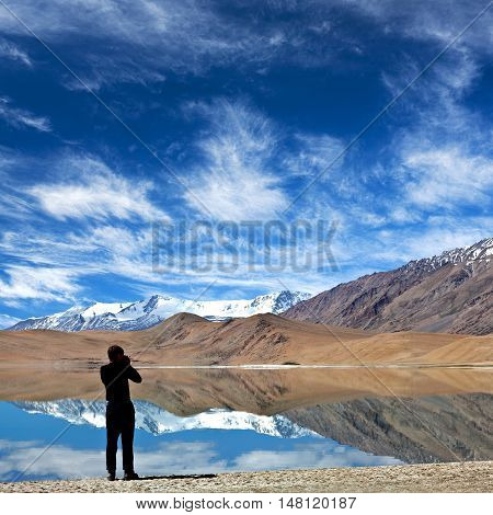 LADAKH, INDIA - JUNE 20, 2012: Tourist with camera walking on Thatsang Karu lake in Ladakh, Jammu and Kashmir State of India