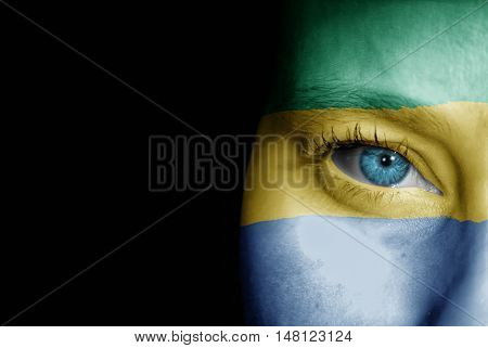 A young female with the flag of Gabon painted on her face on her way to a sporting event to show her support.