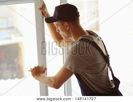 Construction worker installing window in house