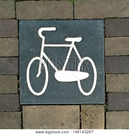 Painted picture of a bicycle on a paving slab surrounded by bricks with space for text.