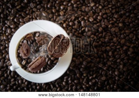 White cup coffee beans with falling beans from top with beans coffee textured background.