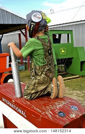 ROLLAG, MINNESOTA, Sept 1. 2016: An unidentified young boy plays on the wood International tractor at the West Central Steam Threshers Reunion in Rollag, MN attended by 1000's held annually on Labor Day weekend.