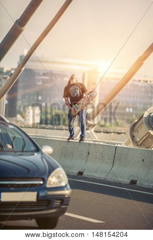 Happy Skateboarder On The Bridge Playing Guitar On His Skate Board