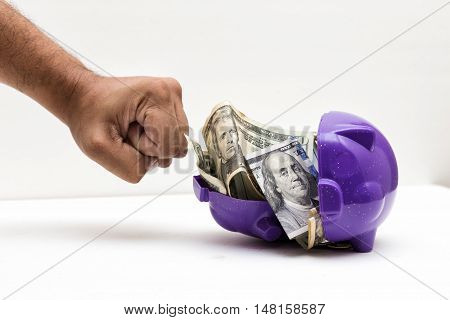A wielded hand braking a piggy bank