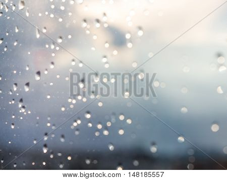 Blurred water drops of rain on blue glass with bokhe as background. Blurred rain drops on window