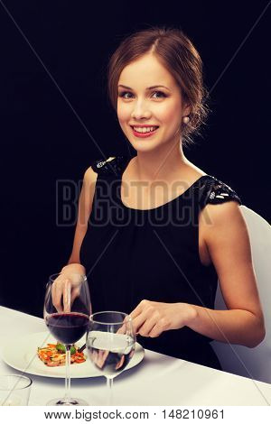 restaurant, people and holiday concept - smiling young woman eating main course at restaurant