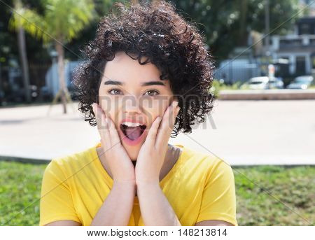 Surprised caucasian girl with curly black hair outdoor in the city in the summer