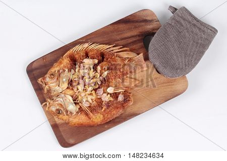 Deep fried fish ,Nile tiapia, with crispy garlic on butcher served isolated white background. Top view.