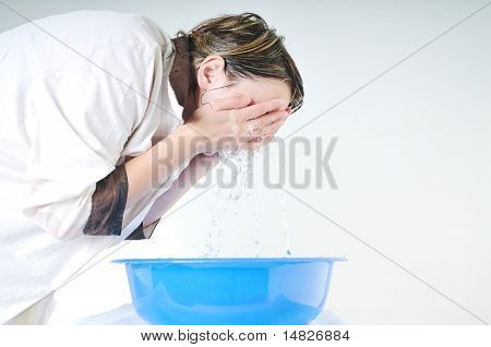 bautiful young woman wash face with clean water isolated on white in studio