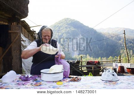 Salciua, Romania - September 14, 2016: Old rural woman selling cheese at the farm in the mountains