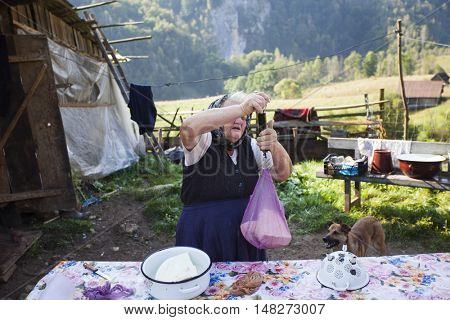 Salciua, Romania - September 14, 2016: Old rural woman selling cheese at the farm in the mountains