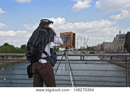 PARIS, FRANCE-AUGUST 09, 2016: photographer with old plate camera on the seine bridge Passerelle Solferino in Paris