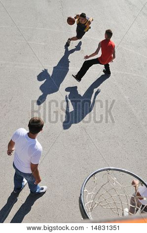 gorup de rapazes que jogar basquete ao ar livre na rua, com longas sombras e bird Ver os psicoló