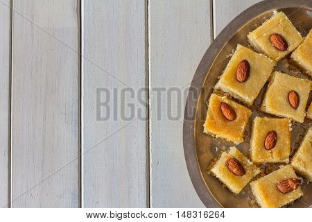 Homemade Basbousa from Above on White Wooden background with Copy Space