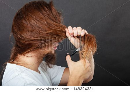 Trim and cut concept. Young handsome man cutting his hair. Change of look. Barber and hairdresser. Back view.