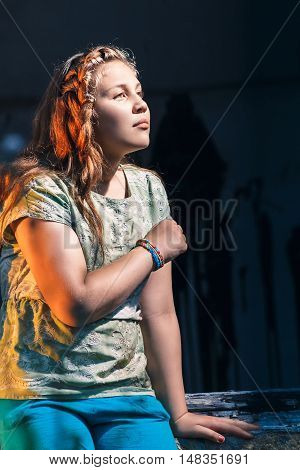 Portrait of a beautiful young teenage girl sitting on window of the old abandoned house