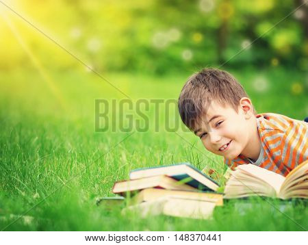 seven years old child reading a book lying on the grass