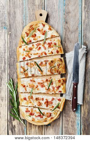 Tart Flambe or Flammkuchen on wooden cutting board. Traditional Alsatian pie. Rustic style, top view.