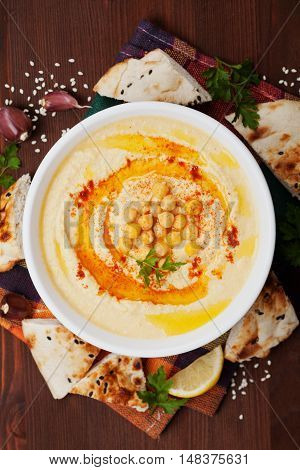 Hummus or houmous appetizer made of mashed chickpeas with tahini, lemon, garlic, olive oil, parsley and paprika. Top view. Flat lay.
