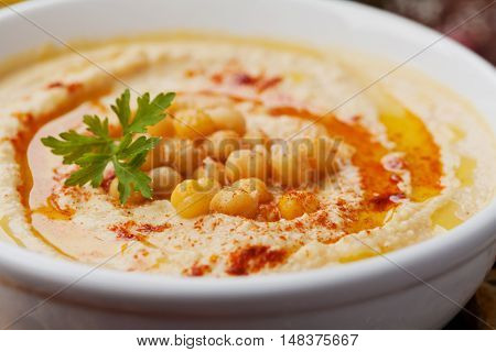 Hummus or houmous appetizer made of mashed chickpeas with tahini, lemon, garlic, olive oil, parsley and paprika.