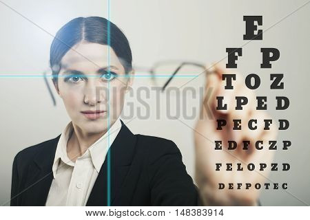 woman glass with laser hologram and test vision table over dark background.