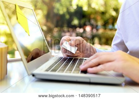 business man entering data of a credit card . On-line shopping on the internet using a laptop