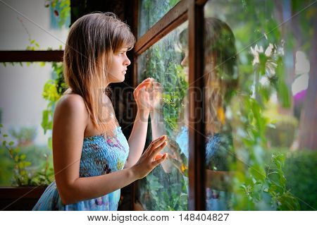 Lonely girl in green gazebo with window on the garden