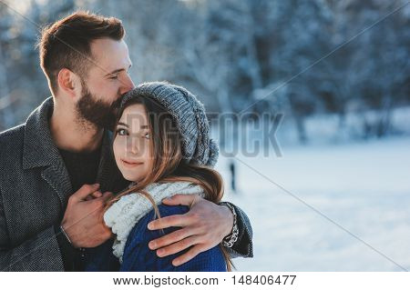 lifestyle shot of young happy couple walking in snowy forest spending winter vacation outdoors