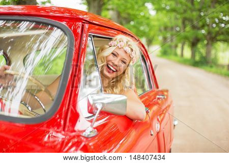 Happy woman driving a  red retro car