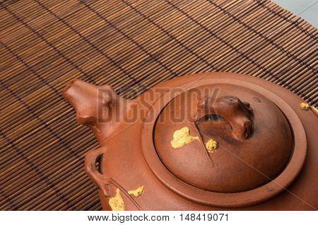 brown Chinese teapot of Yixing clay with traditional ornament on bamboo Mat